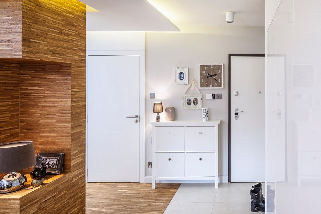 Partition clad in engineered wood and white chest of drawers between doors in hallway