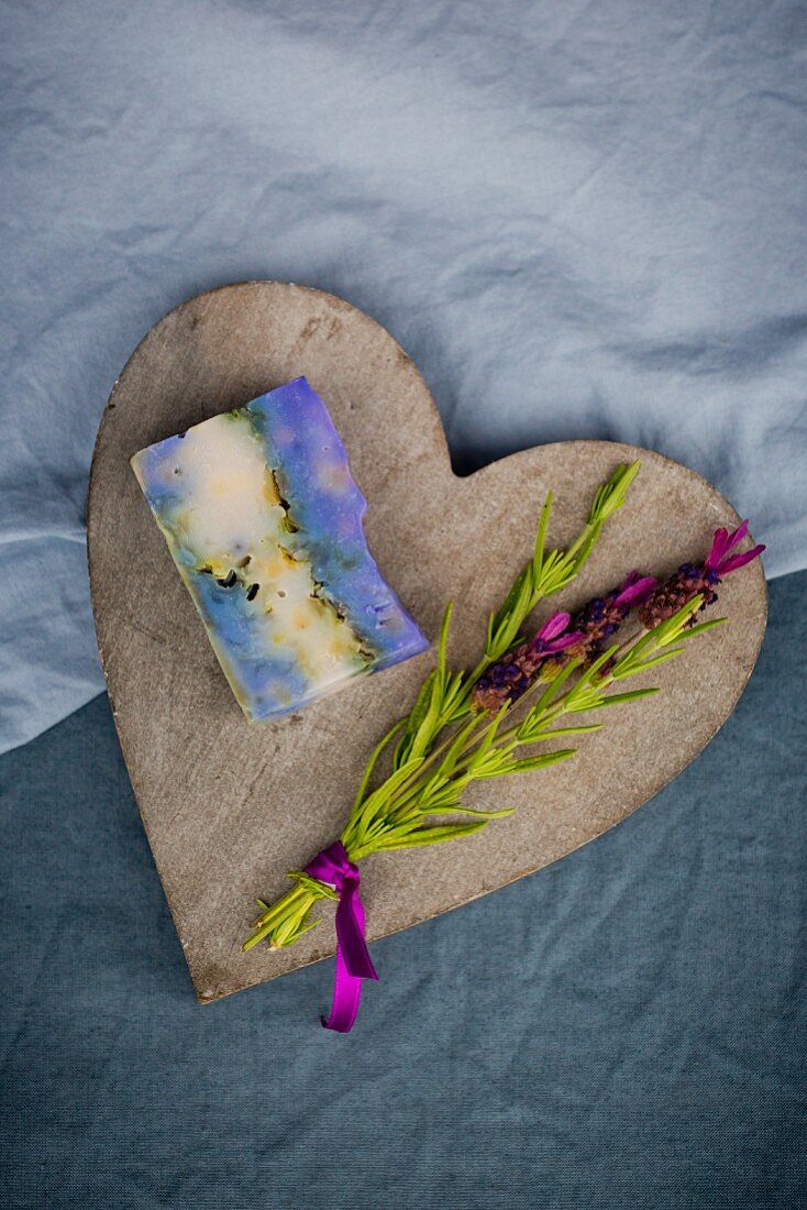 Bar of handmade lavender soap and sprig of fresh lavender on wooden heart