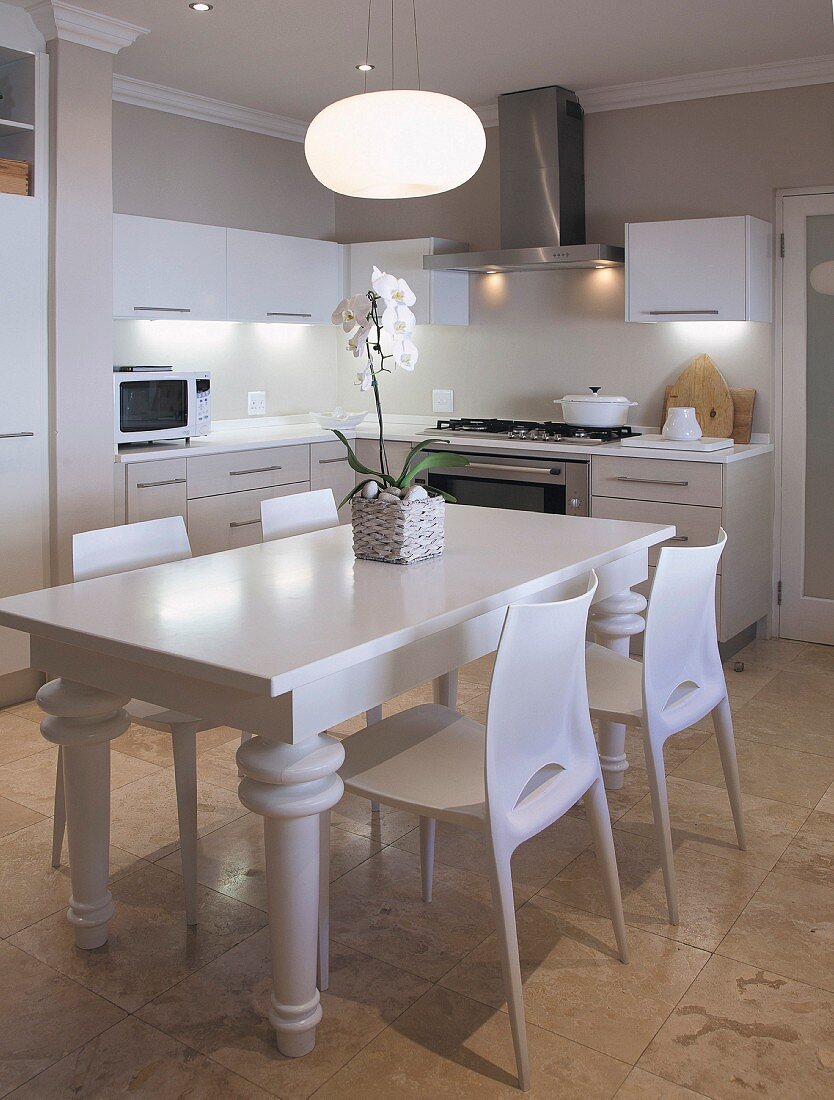 White dining area with modern chairs around rustic wooden table painted white in contemporary kitchen