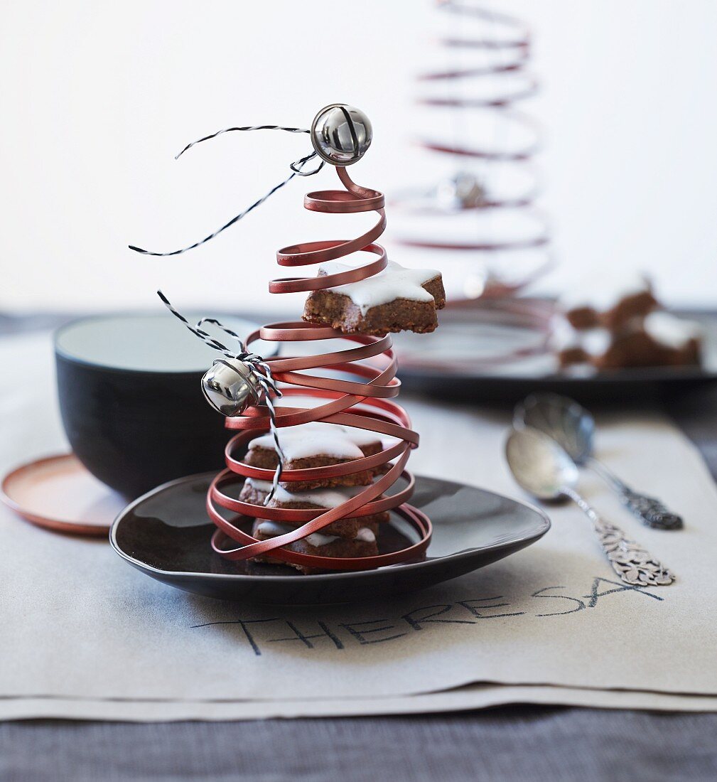 Christmas tree ornaments made from coiled copper wire, bells and cinnamon stars decorating table