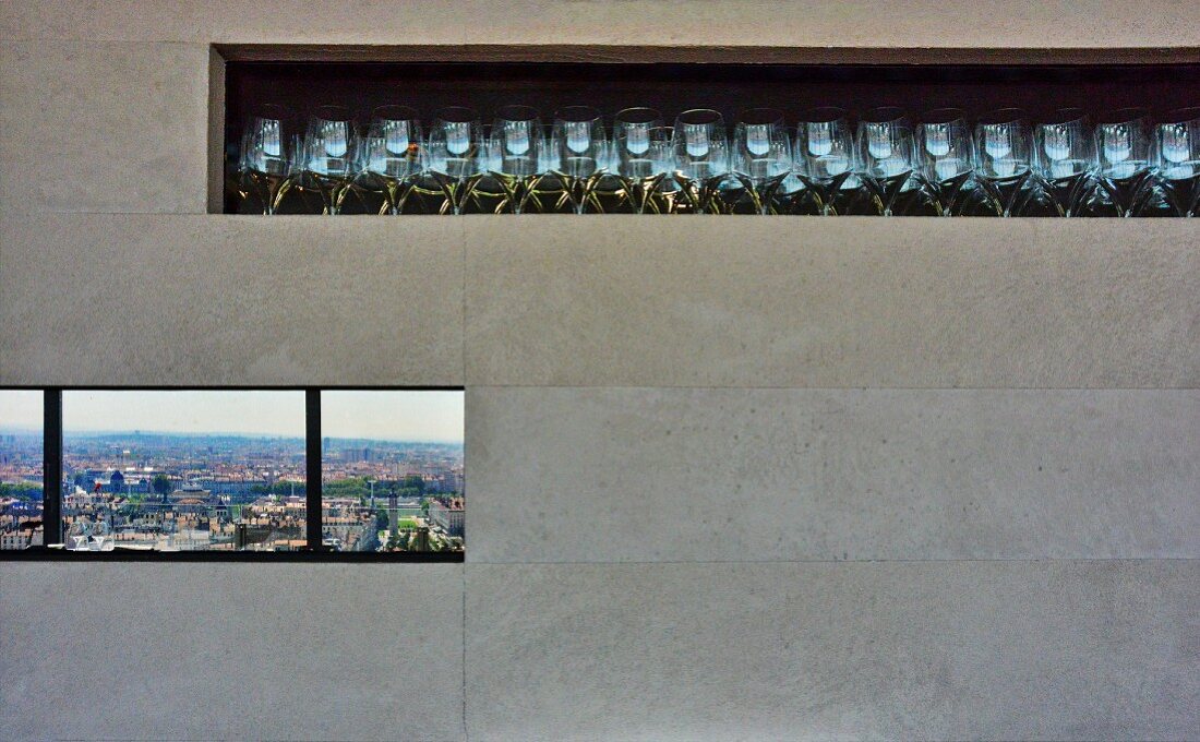 Gläser in Wandnische mit Steinfliesen über Fensterband mit Stadtblick