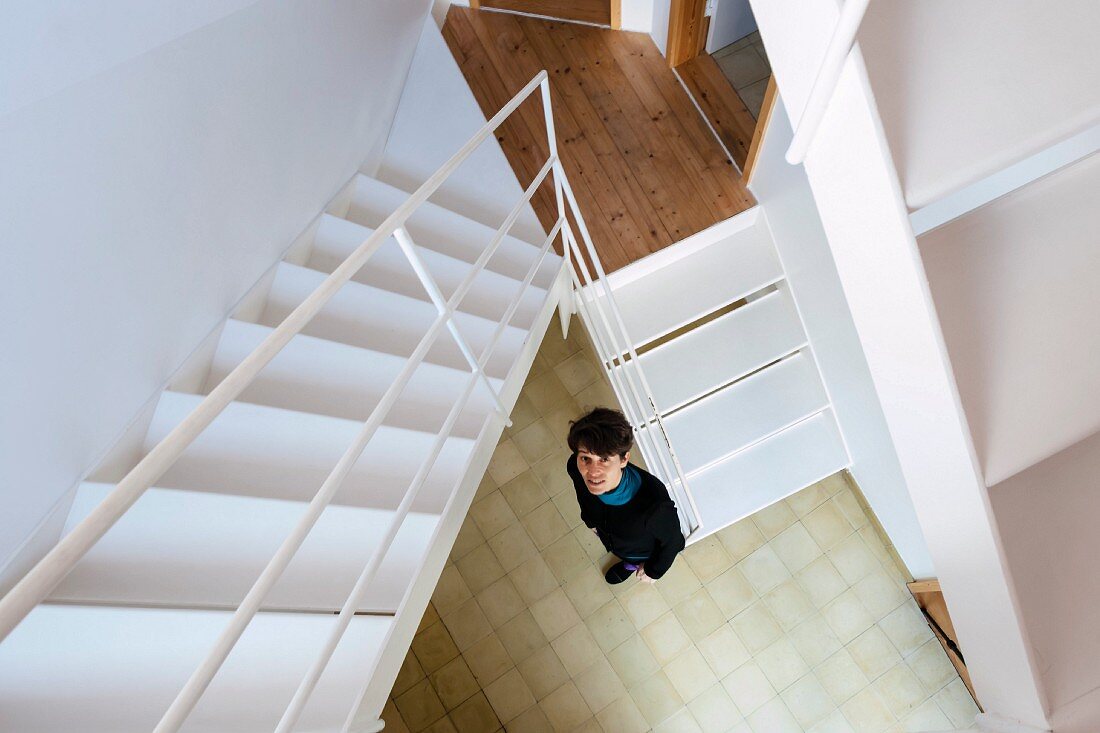 Blick von weißer Stahltreppe auf Frau im Treppenauge stehend