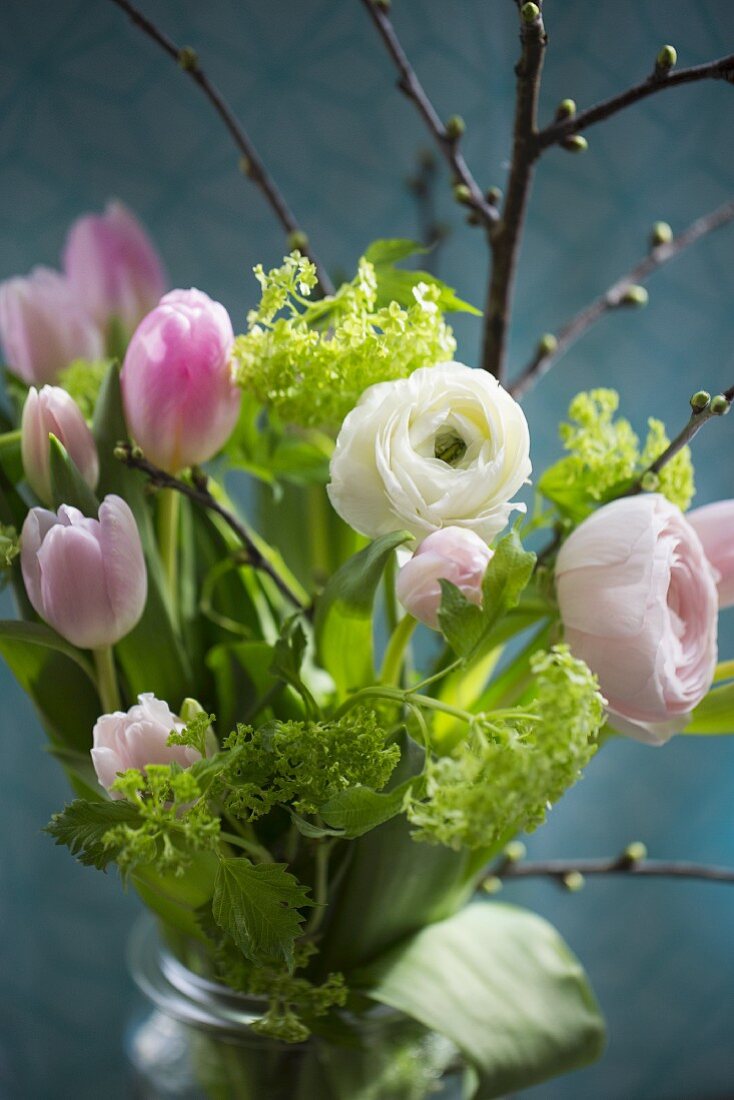 Tulpen, Schneeball, Ranunkeln und Kirschzweig im Wasserglas