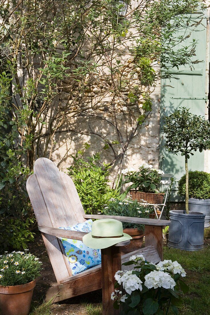 Naturbelassener Deckchair im Garten mit vielen Blumentöpfen und Pflanzen