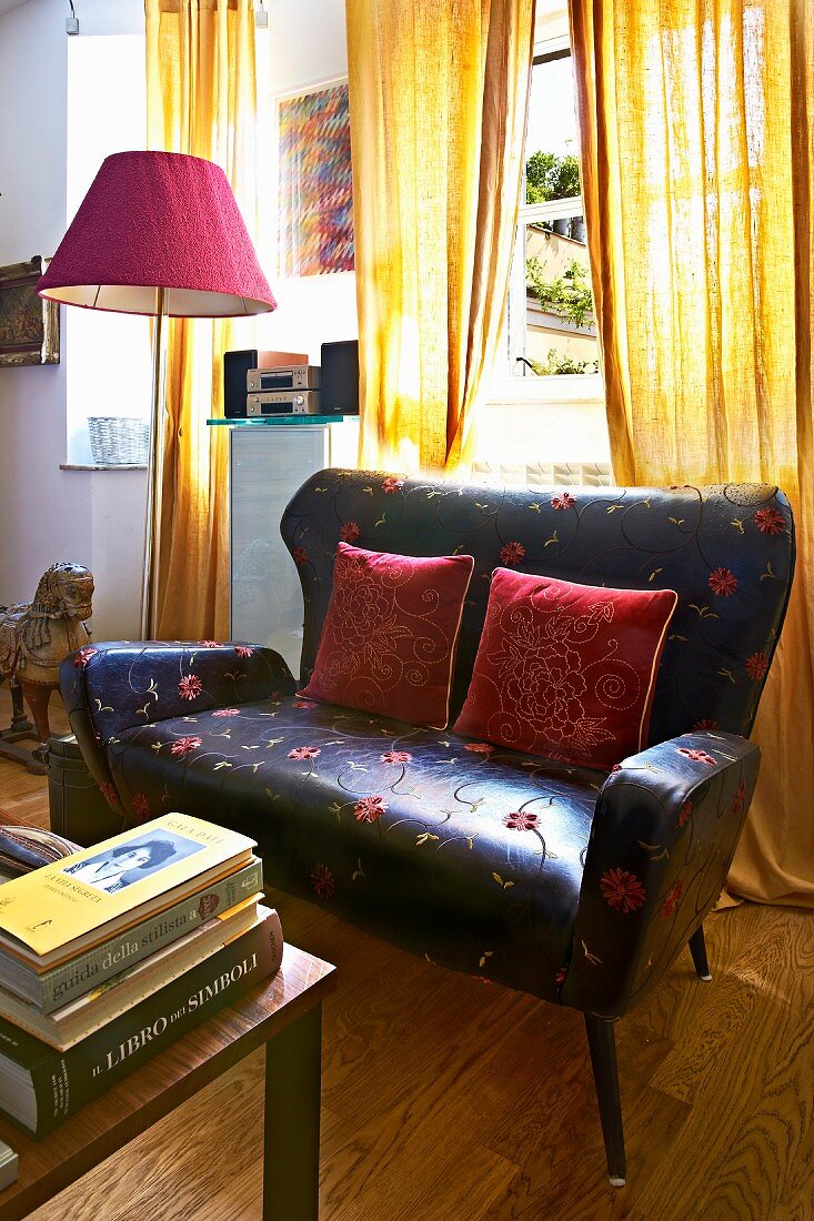 Bodenlanger gelber Vorhang hinter elegantem Retro Ledersofa mit roter Stehlampe
