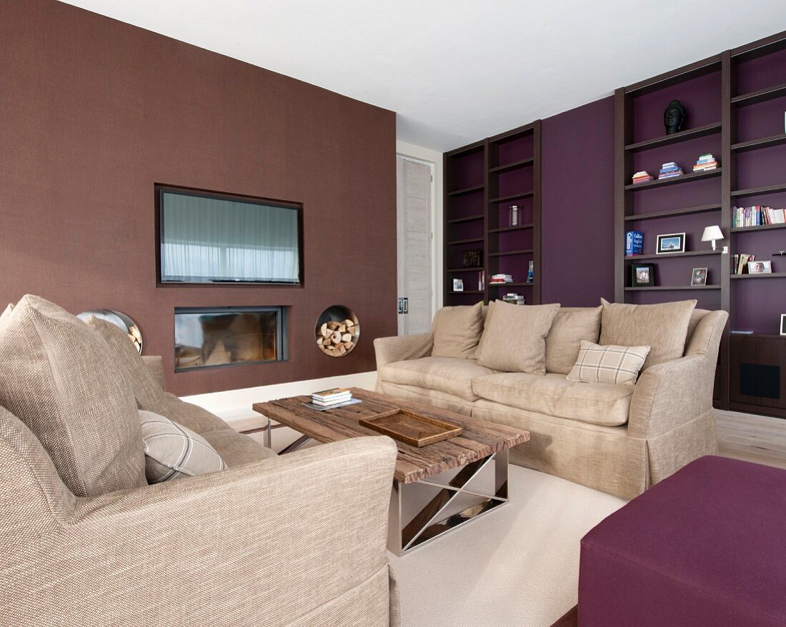 Wohnzimmer in warmen Tönen mit Einbauregal, gegenüberstehenden Sofas und Kamin