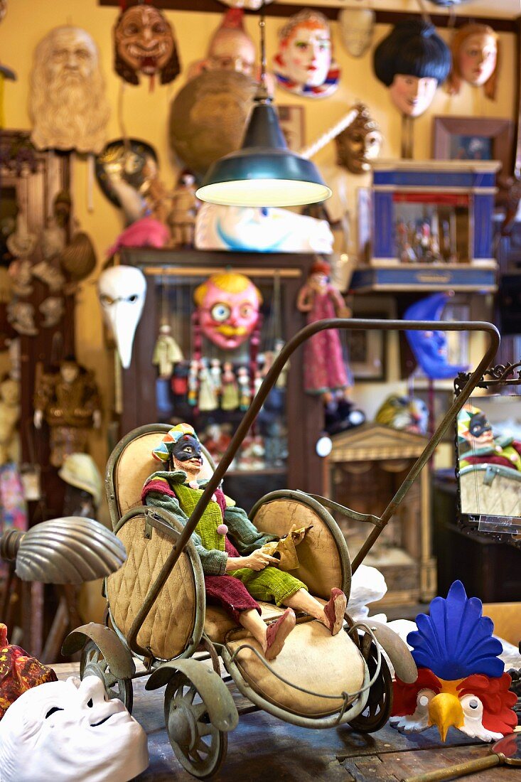 Vintage Puppenwagen mit Figur in Werkstatt eines Masken-Bildhauers