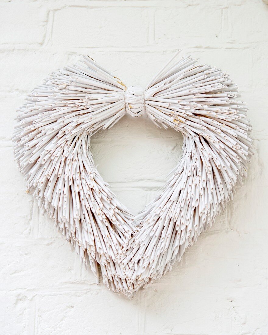 Heart-shaped wreath of whitewashed straw hung on wall