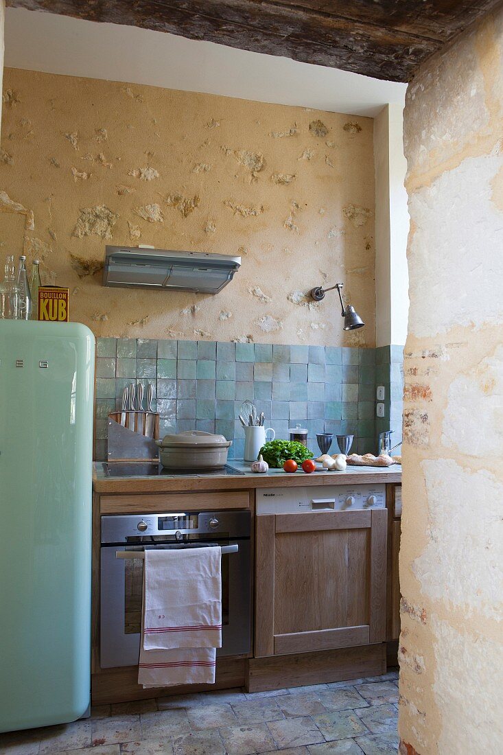 Blick in rustikal ländliche Küche mit Retro-Kühlschrank und Küchenzeile mit Holzfront