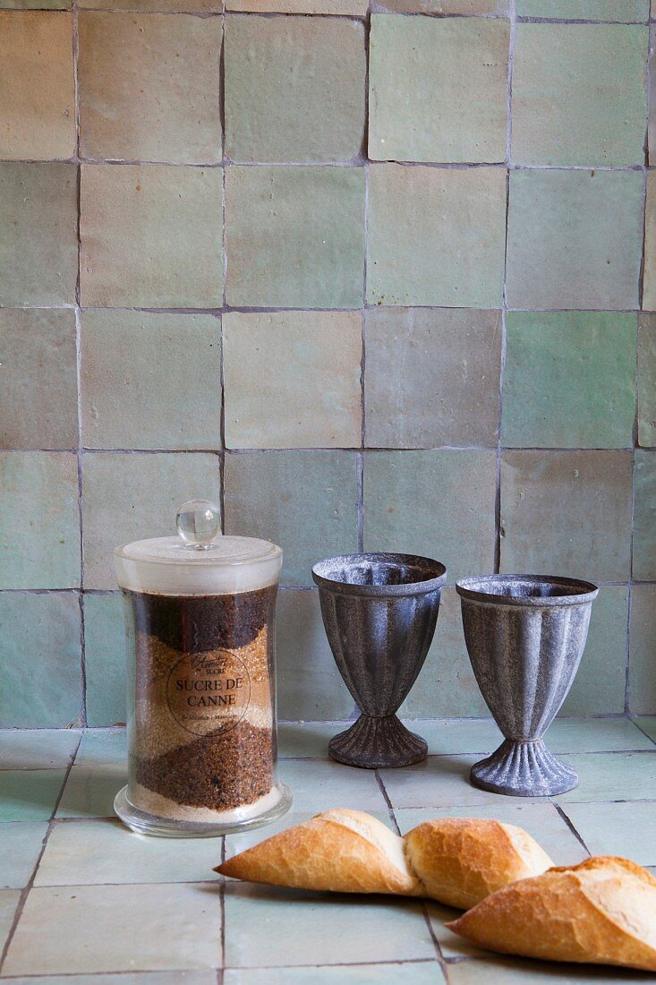 Still-life arrangement of antique drinking cups against kitchen wall with rustic tiles