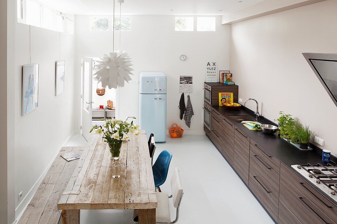 Küche mit langer Küchenzeile und rustikalem Holztisch, im Hintergrund Retrokühlschrank