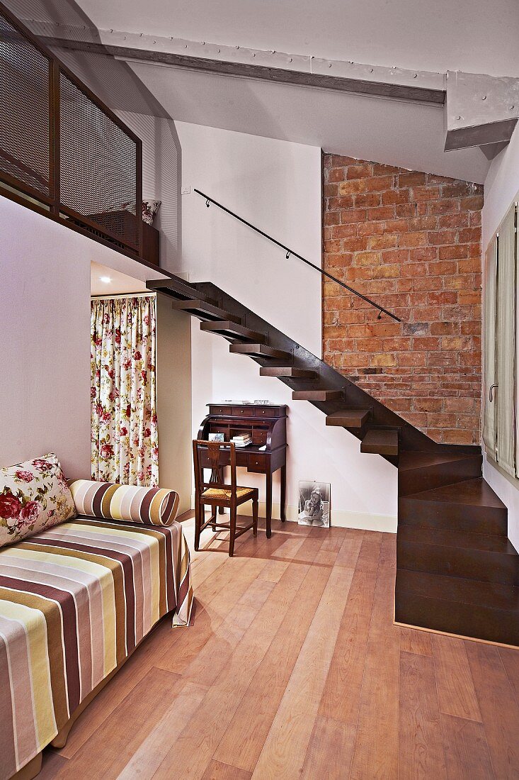 Tagesliege mit gestreiftem Überwurf in renoviertem Zimmer, Designer-Treppe aus Edelholz zur Galerieebene