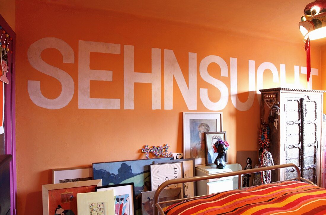Detail of bedroom with motto on orange wall