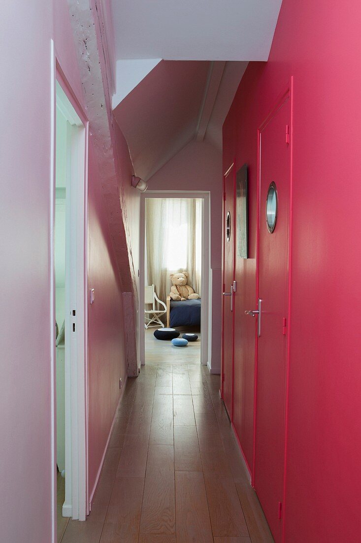 Pink wall with porthole windows in doors in narrow hallway