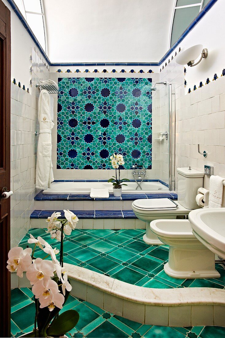 Luxuriös gestaltetes Bad mit geschwungener Stufe, grüner Fliesenboden, im Hintergrund eingebaute Badewanne, an Wand grün-blaue Fliesen mit Blumenmuster (Villa Cimbrone Hotel)