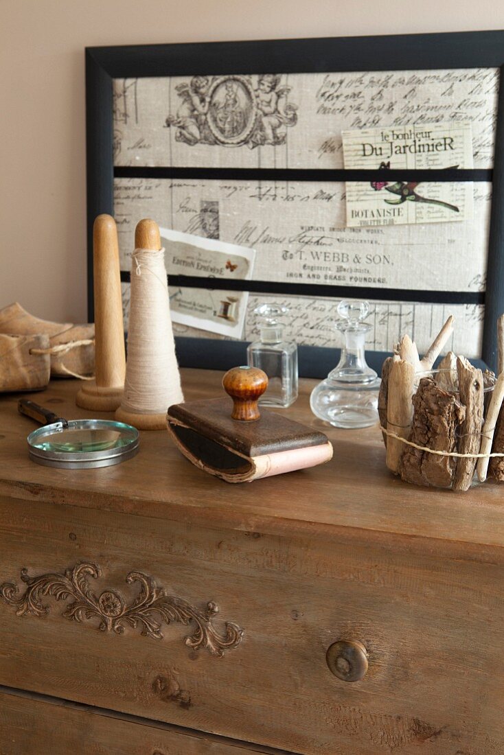 Spindles, vintage stamp and bundle of driftwood on top of chest of drawers with vintage picture frame in background