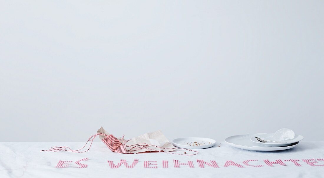 Table cloth with festive, pink embroidered motto, used plates and crumpled wrapping paper