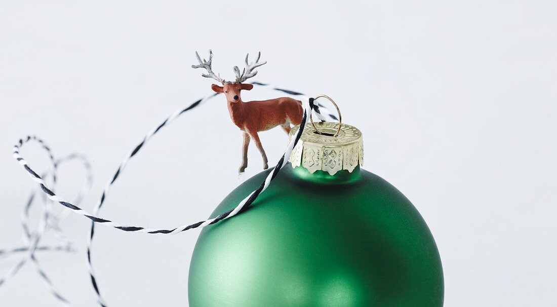 Green Christmas bauble decorated with miniature reindeer figurine
