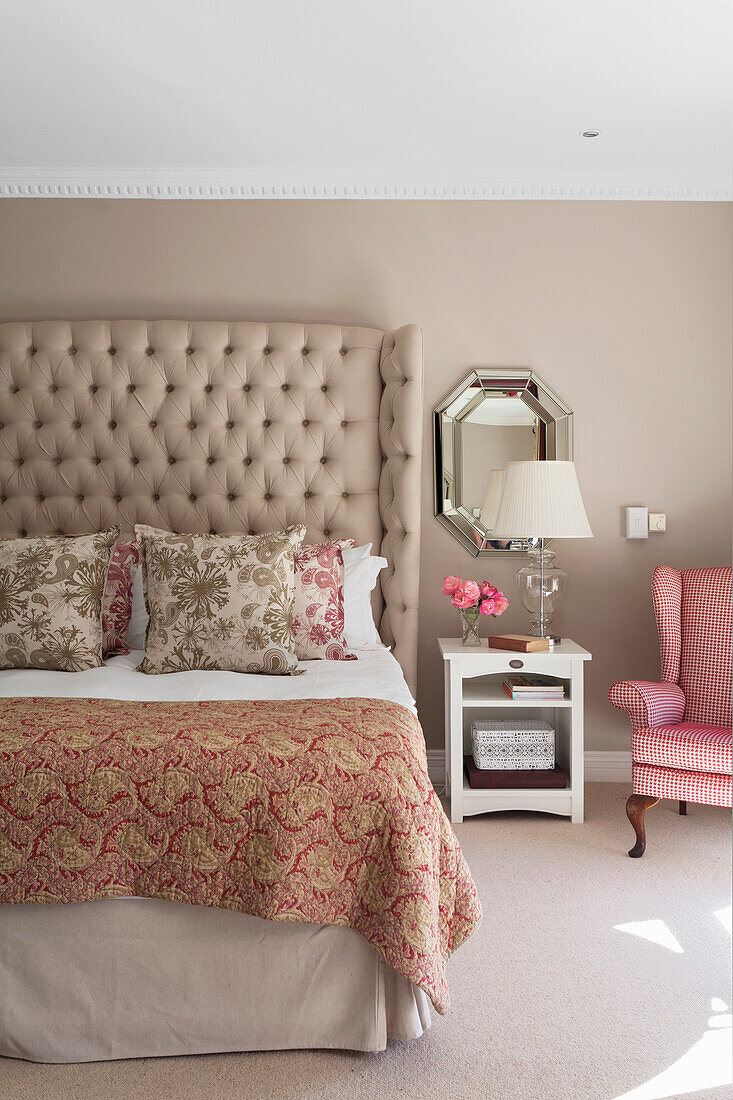 Upholstered bed with patterned bedspread and chequered armchair