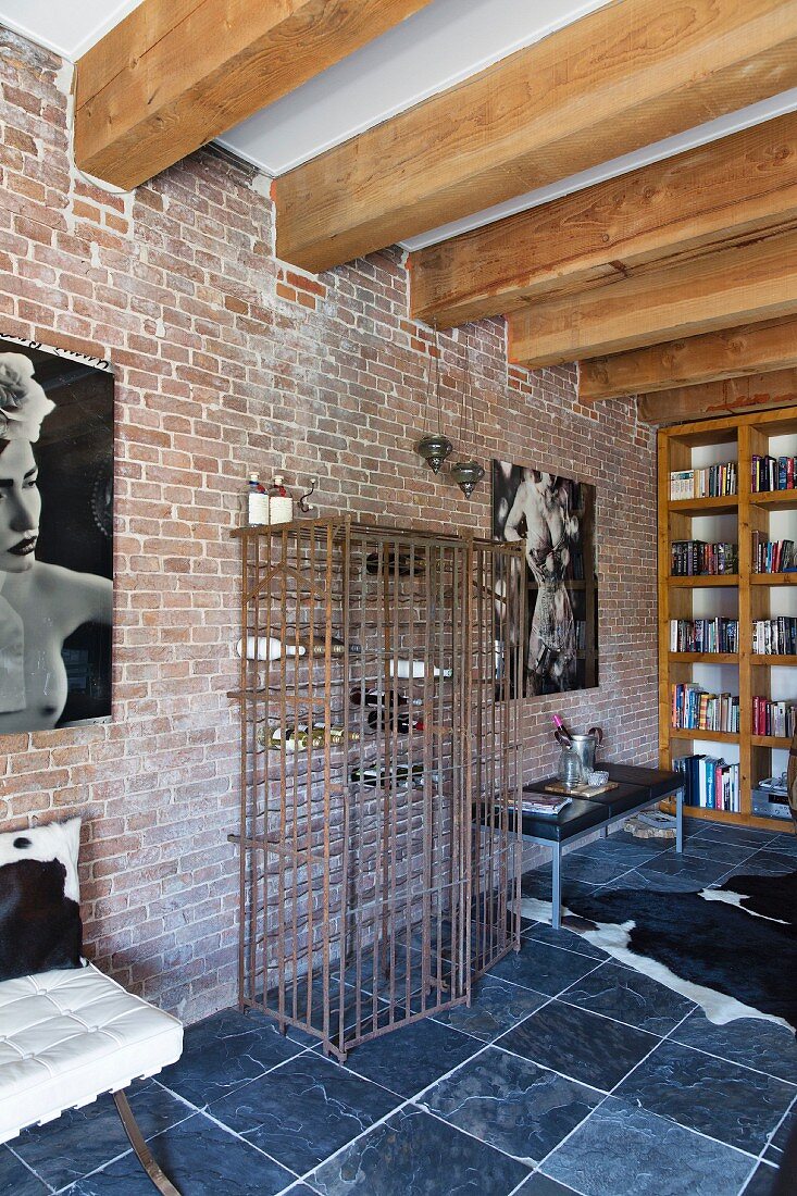 Wood-beamed ceiling, slate floor and metal-cage wine rack against brick wall in loft apartment