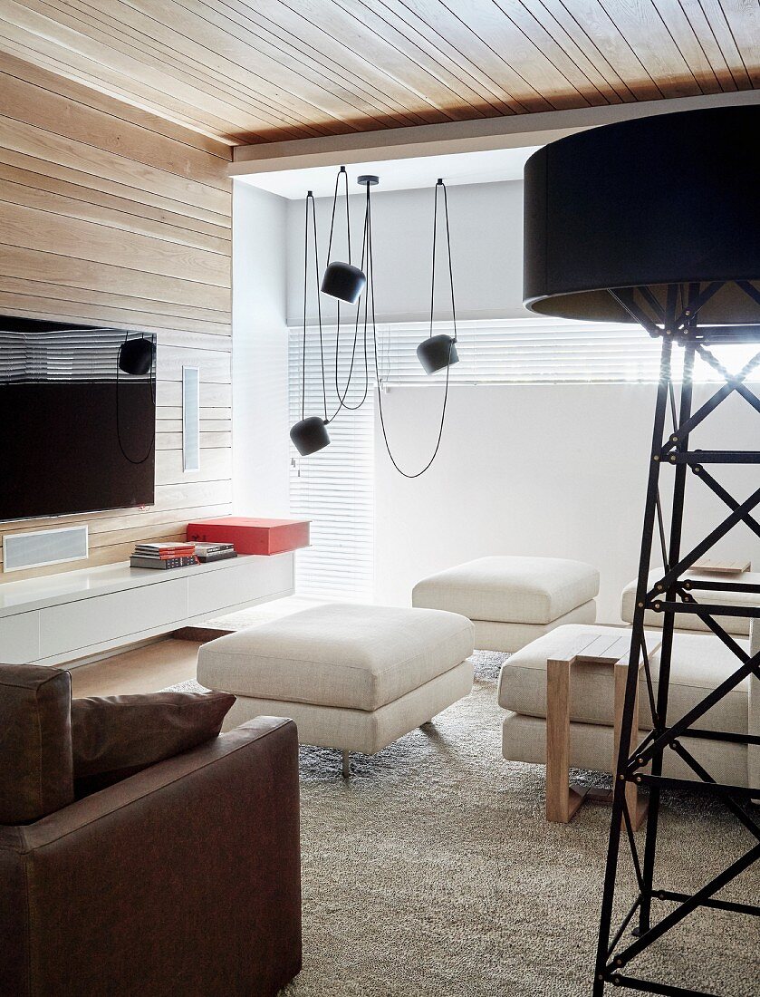 Modernes Wohnzimmer mit großer Standleuchte und Holzverkleidung
