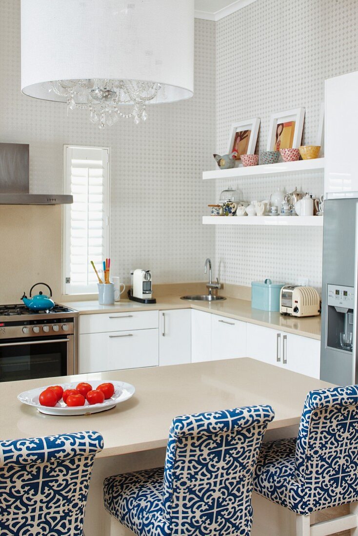 Gepolsterte Barhocker mit weiss blau gemustertem Bezug an Frühstückstheke in modernem Kochbereich