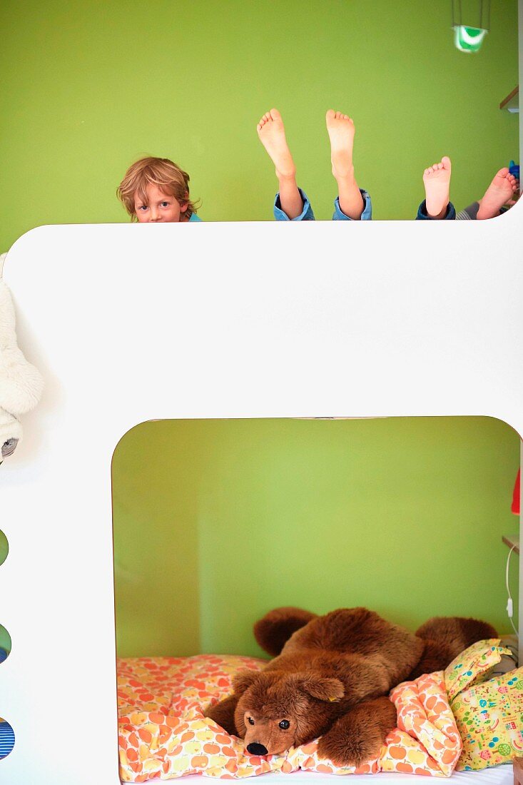 Kinder auf Etagenbett vor grün getönter Wand
