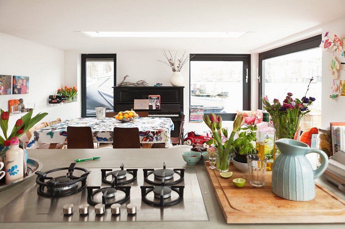 View past flowers and gas hob on island counter into dining area of houseboat