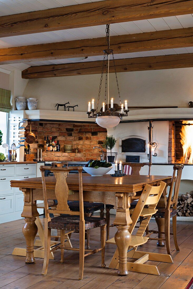 Rustikaler Esstisch mit Holzstühlen und Hänge-Kerzenleuchter in Küche mit Holzbalkendecke