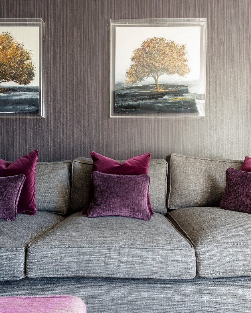 Grey sofa, dark red scatter cushions and grey and brown striped wallpaper