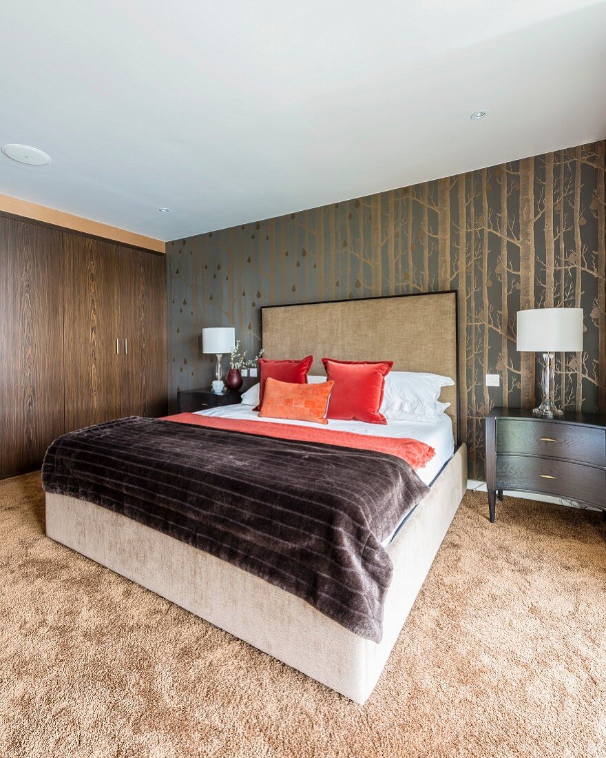 Double bed with tall headboard, wallpaper with pattern of birch trees and long-pile carpet in bedroom