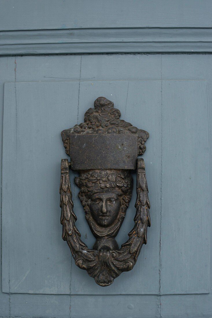 Vintage Türklopfer aus Metall mit Kopfmotiv auf blaugrau gestrichener Tür