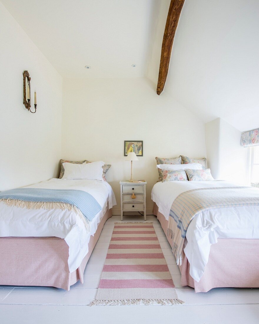 Pink and white striped rug between twin beds in rustic bedroom