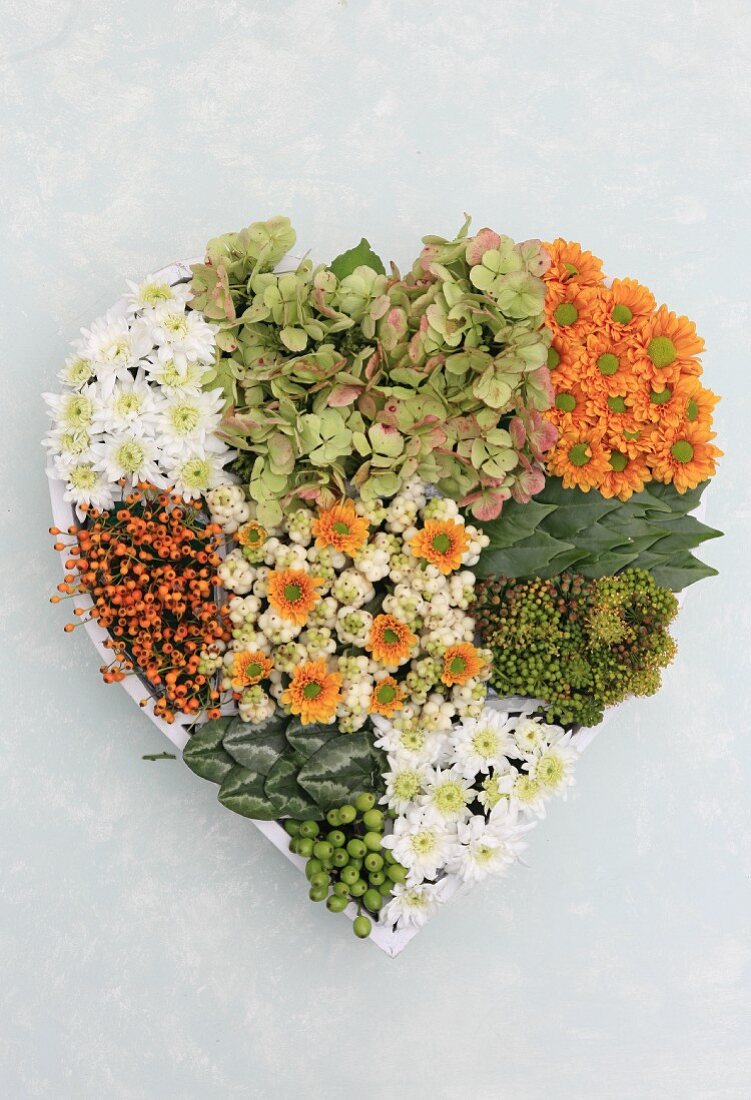 Selbst gebasteltes Blumengesteck aus Chrysanthemen, Hortensien und Beeren in Herzform