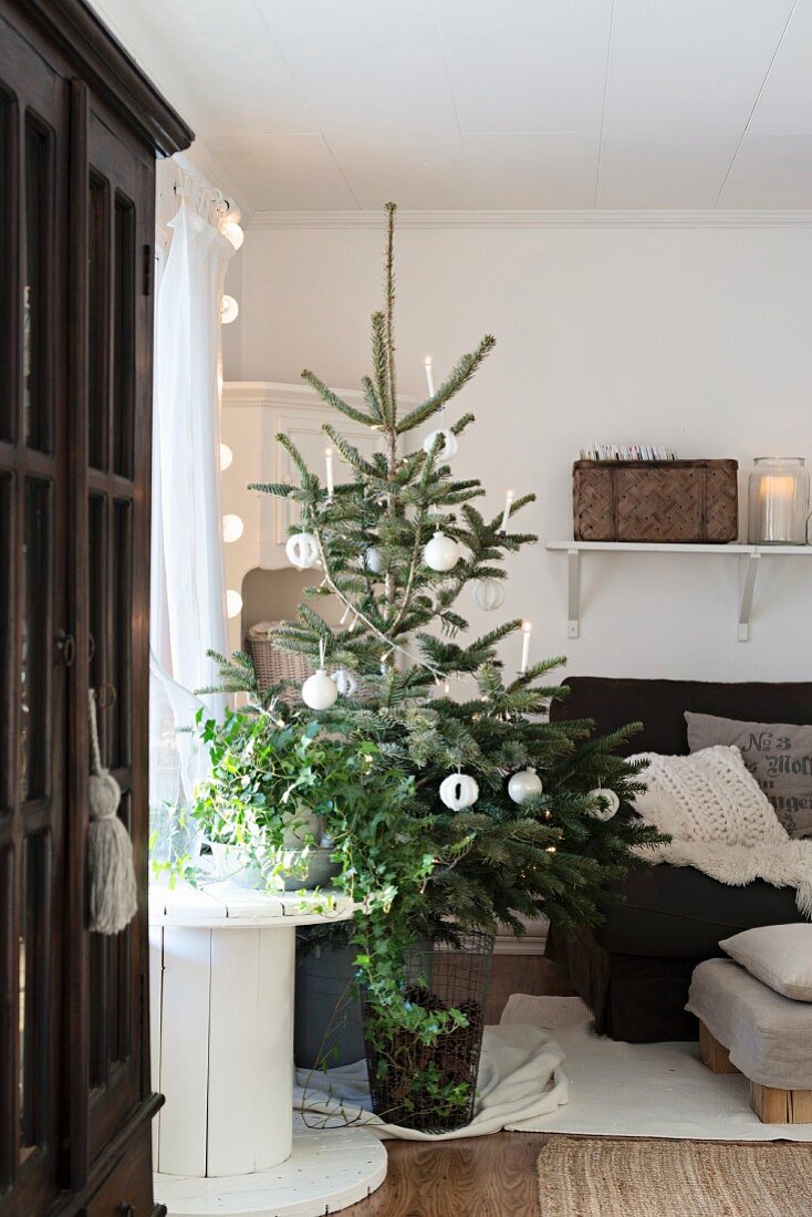 Schlicht geschmückter Weihnachtsbaum neben Kabelrolle und Sessel