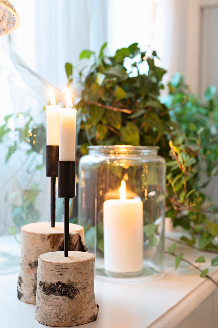 Lit candles in birch stump holders and in preserving jar