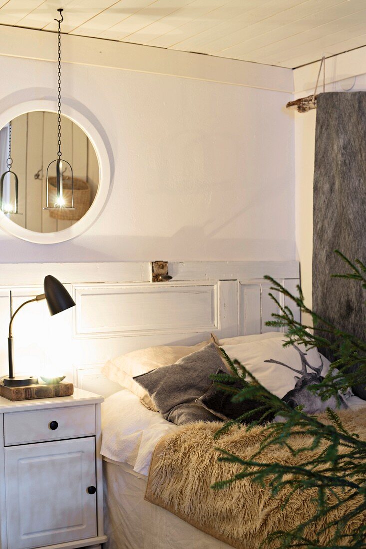 Winterliches Schlafzimmer mit Felldecke und warmem Licht, Tannenbaum im Anschnitt