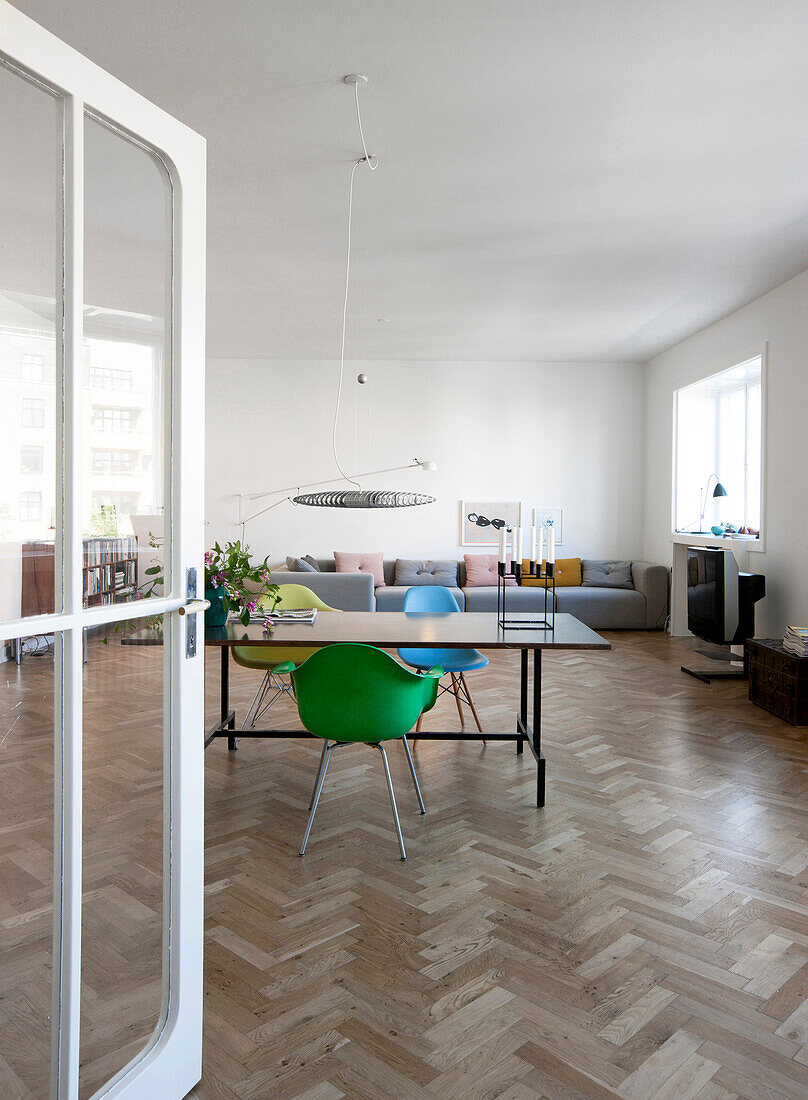 Open glass door leading into interior with herringbone parquet floor and designer furniture