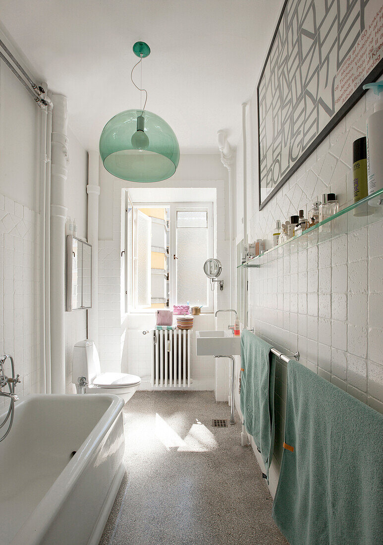 Mint-green glass lamp in long, narrow bathroom