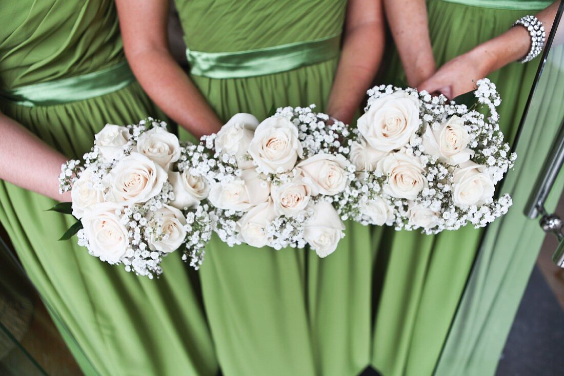 Three bridesmaids holding posies of white roses