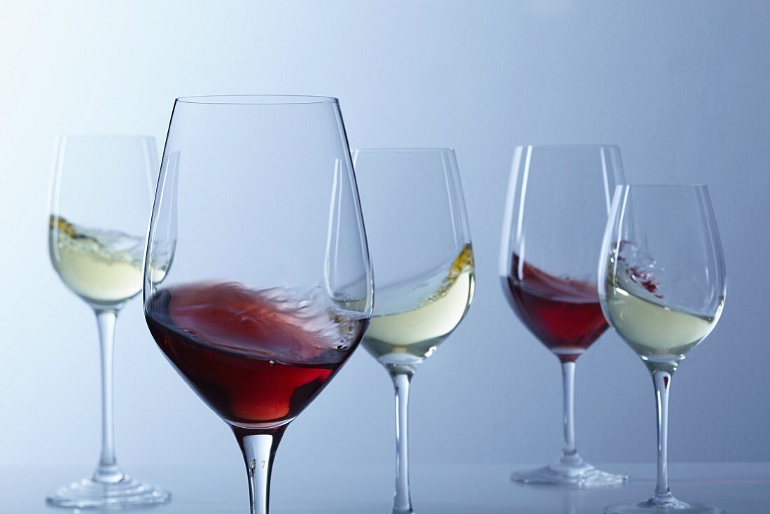 Rotwein und Weißwein schwappt in Gläsern