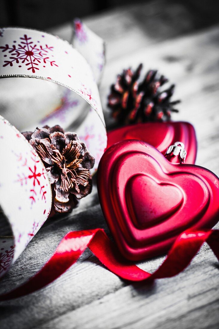 Rote Herzen als Weihnachtsschmuck, Kiefernzapfen und Geschenkbänder