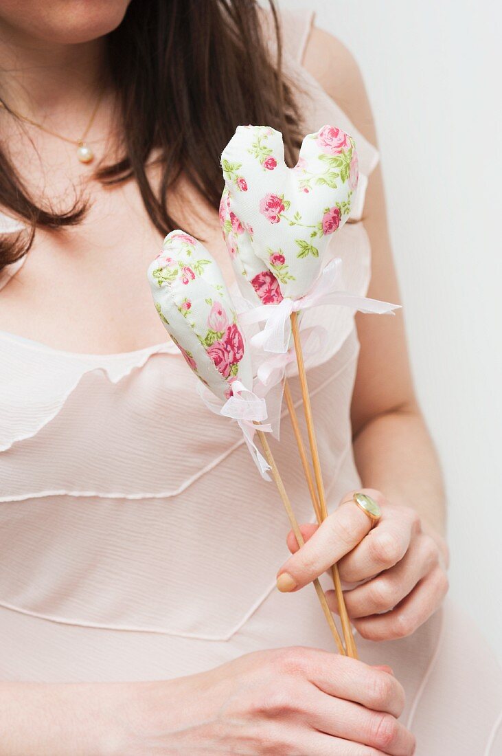 Woman holding floral, fabric love-heart on wooden stick