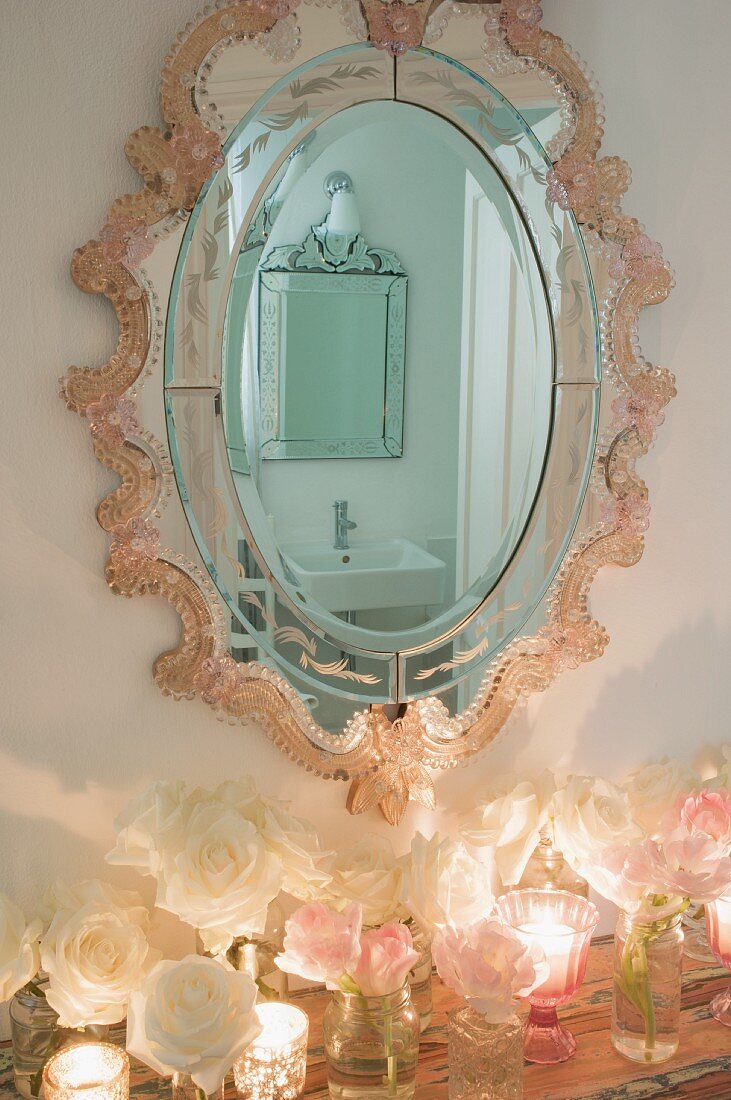 Romantisch verzierter Ovalspiegel mit Badezimmer Reflektionen, darunter romantische Deko mit Rosen und Windlichtern