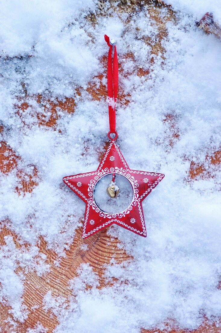 Red, festive star with artificial snow on cross-grained wood