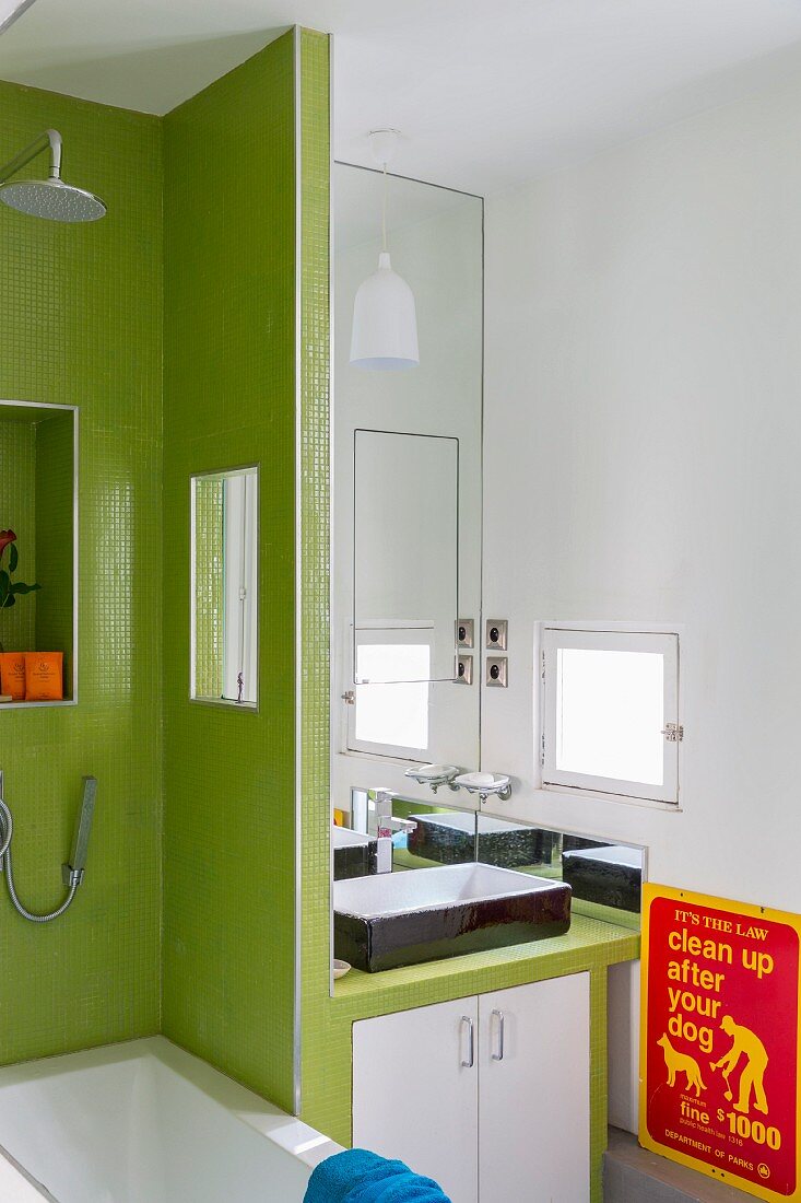 Waschtisch mit Unterschrank, neben Trennwand mit grünen Mosaikfliesen