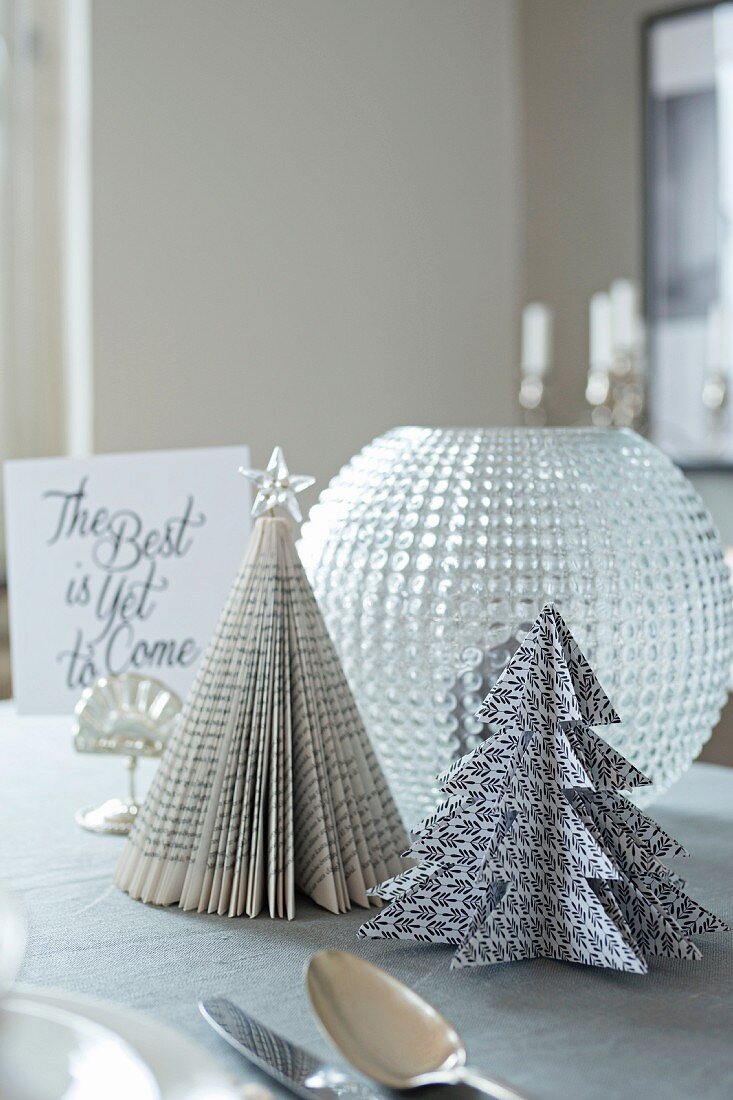 Festive Christmas tree ornaments made from folded black and white paper and book pages on table