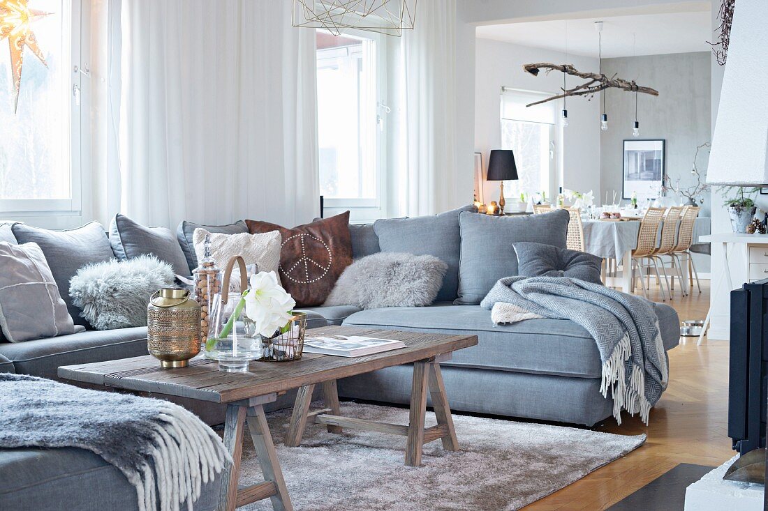 U-förmiges Sofa in Grautönen mit rustikalem Couchtisch auf Böcken in offenem Wohnbereich
