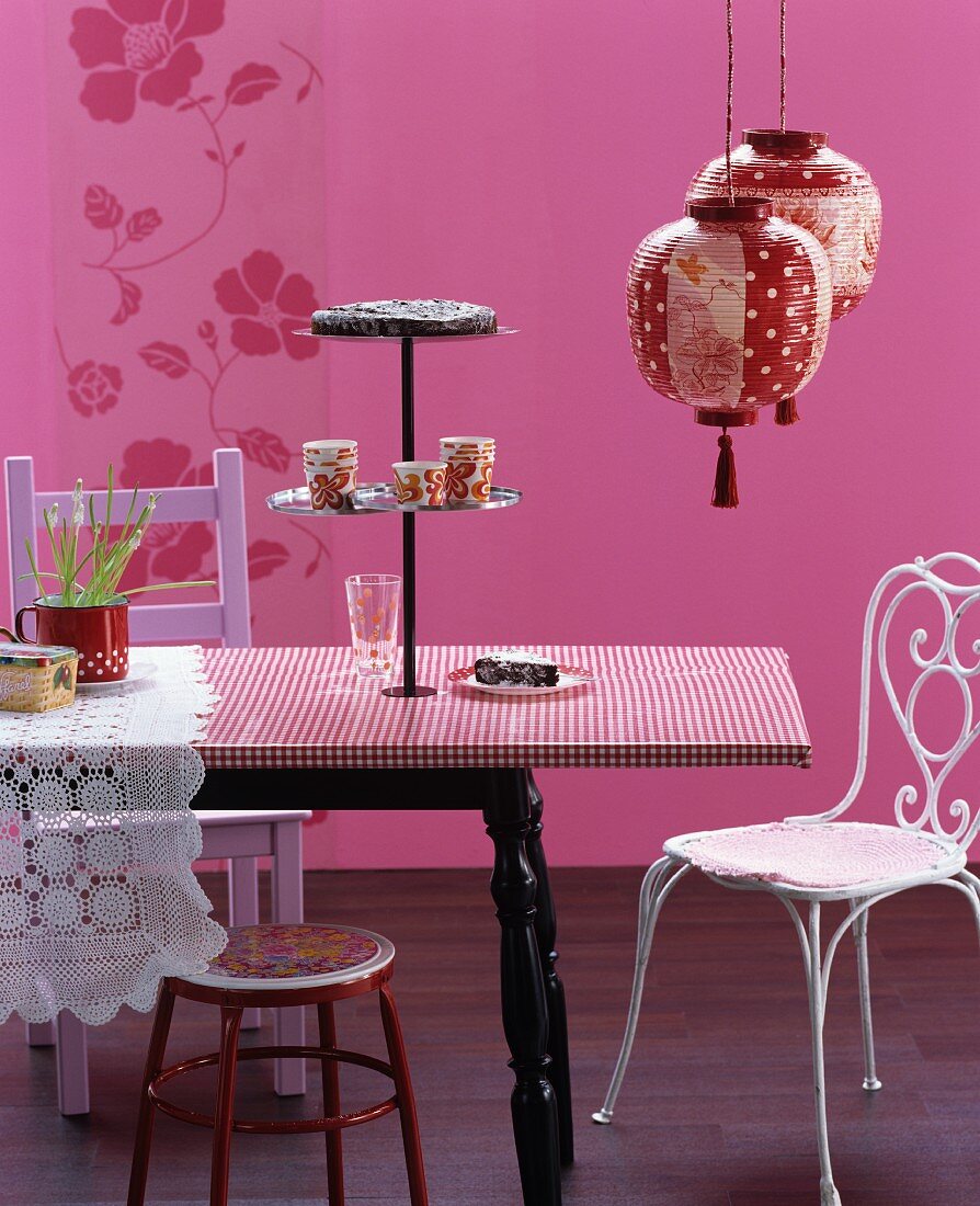 Stilmix in Pink: Esstisch mit Etagere, verschiedenen Stühlen und asiatischen Papierlampen