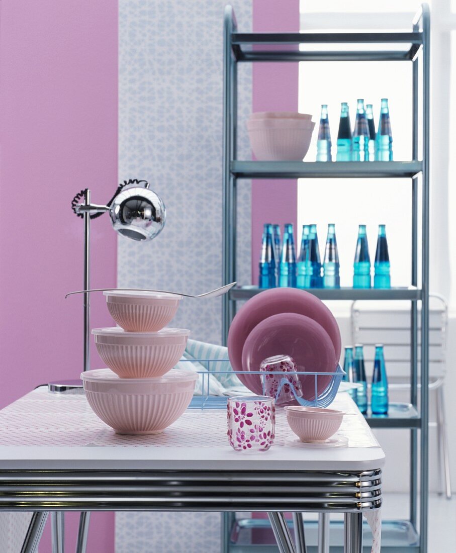 Kultiges Edelstahlregal, verchromter Esstisch und pinkfarbenes Zubehör im Fiftiesstil für die Küche
